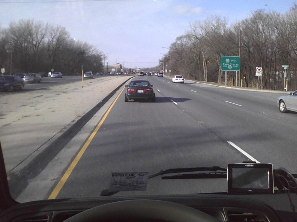 Dark sedan driving on a highway, seen from inside another vehicle