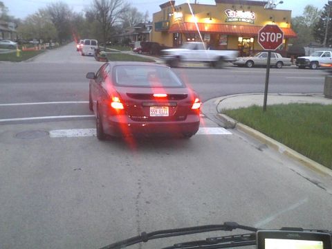2003 Ford Crown Victoria - Red sedan waits at a crosswalk near a restaurant, with traffic in the background.