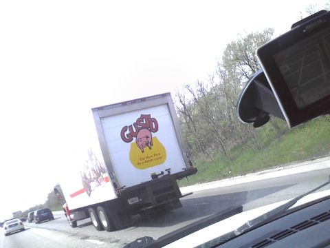 2003 Ford Crown Victoria - A Gusto Foods truck is seen on the highway, advertising 'Eat More Pork. Be a Better Lover.'