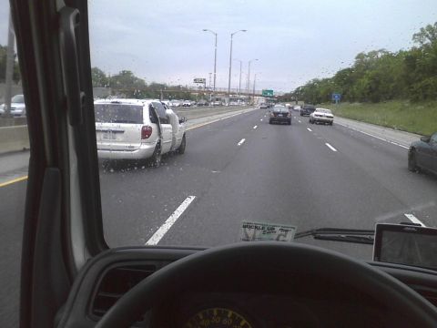 2003 Ford Crown Victoria - A white minivan is stopped on the highway with its doors open, while other vehicles pass by.