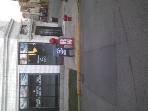 2003 Ford Crown Victoria - A street scene shows a red fire hydrant and newspaper boxes outside a storefront with advertisements in the windows.