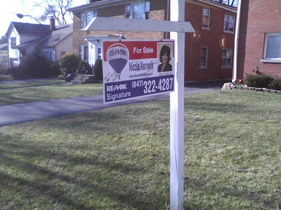 RE/MAX For Sale sign with agent Nicole Norwalk's contact info and photo in front of a house