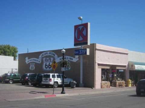 1991 Ford LTD Crown Victoria - Route 66 mural on a building in Williams, Arizona, with several vehicles parked nearby.