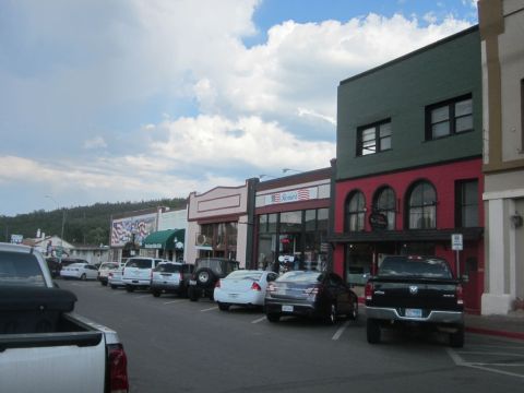 1991 Ford LTD Crown Victoria - A row of shops lines a street where several vehicles are parked under a partly cloudy sky.