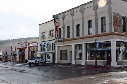 1991 Ford LTD Crown Victoria - A white pickup truck is parked on a wet street in a historic town with a prominent "HOTEL" sign.