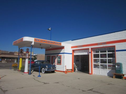 1991 Ford LTD Crown Victoria - A classic dark blue sedan is parked under the canopy of Pete's Gas Station Museum, a Route 66 landmark.