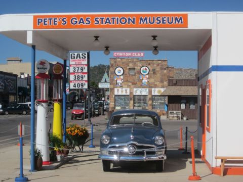 1991 Ford LTD Crown Victoria - A classic Ford sedan is displayed at Pete's Gas Station Museum, vintage gas pumps and signage.