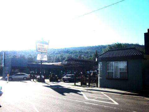 1991 Ford LTD Crown Victoria - A silver sedan is parked in front of the Grand Motel, with a wooded hillside visible behind the building.