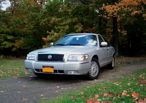 2008 Mercury Grand Marquis - A silver 2008 Mercury Grand Marquis is parked on a gravel road with autumn foliage in the background.