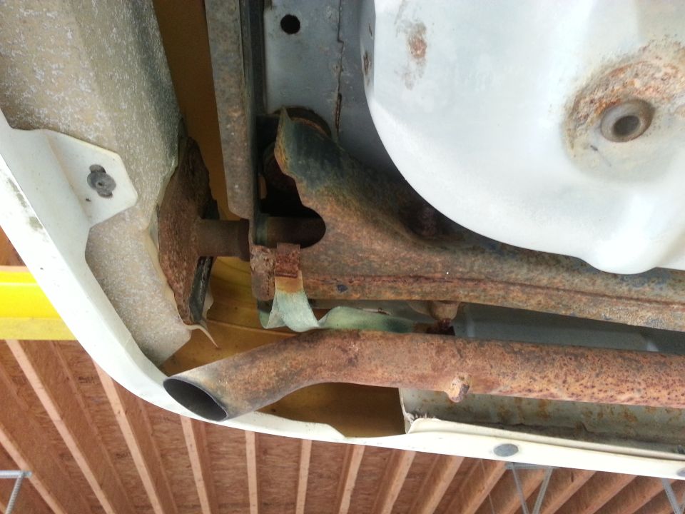 Rusty underside exhaust pipes and frame rails of a vehicle