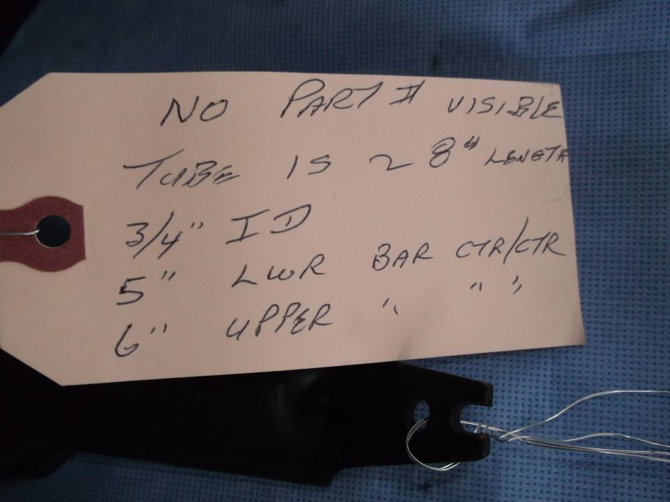 Black metal part with a tag that reads 'NO PART # VISIBLE TUBE IS 28" LENGTH 3/4" ID 5" LWR BAR CTR/CTR 6" UPPER'