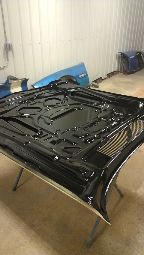 1973 Chevrolet Camaro - The underside of a black car hood is shown, with other car parts visible in the background.