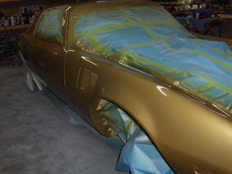 1973 Chevrolet Camaro - A gold-colored car is being prepped for a new paint job, with masking tape covering the hood and roof.