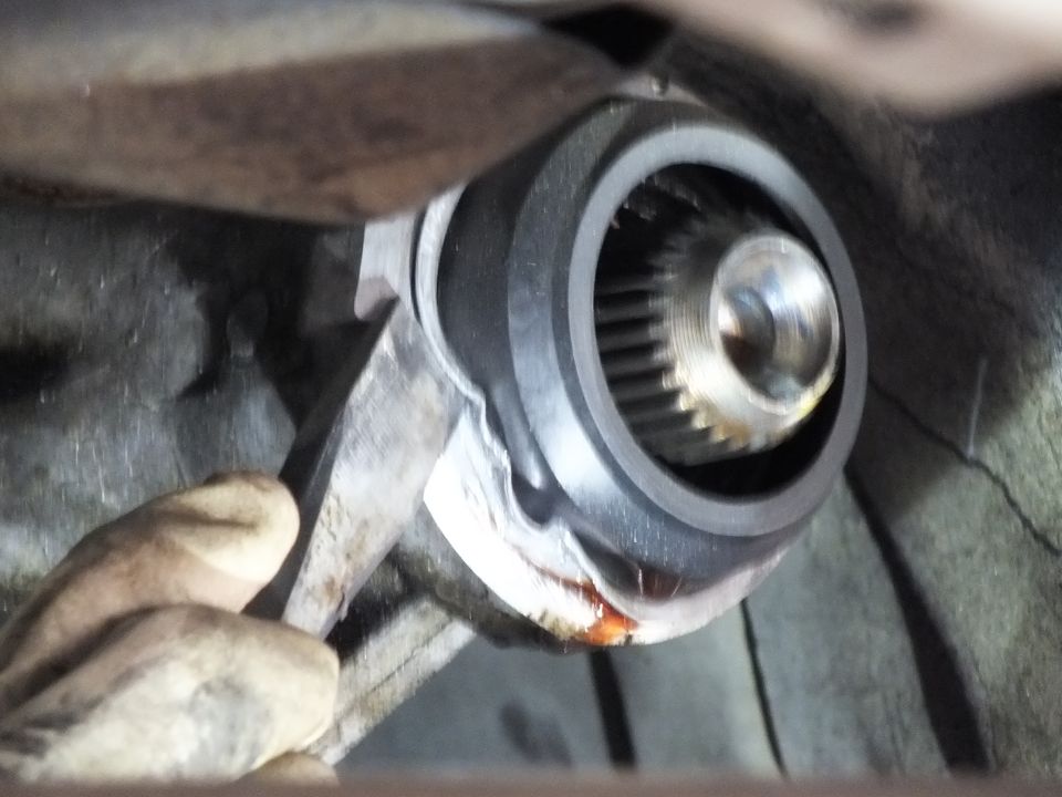 Close-up of splined driveshaft yoke slip joint with center bolt, gloved hand and pry bar nearby