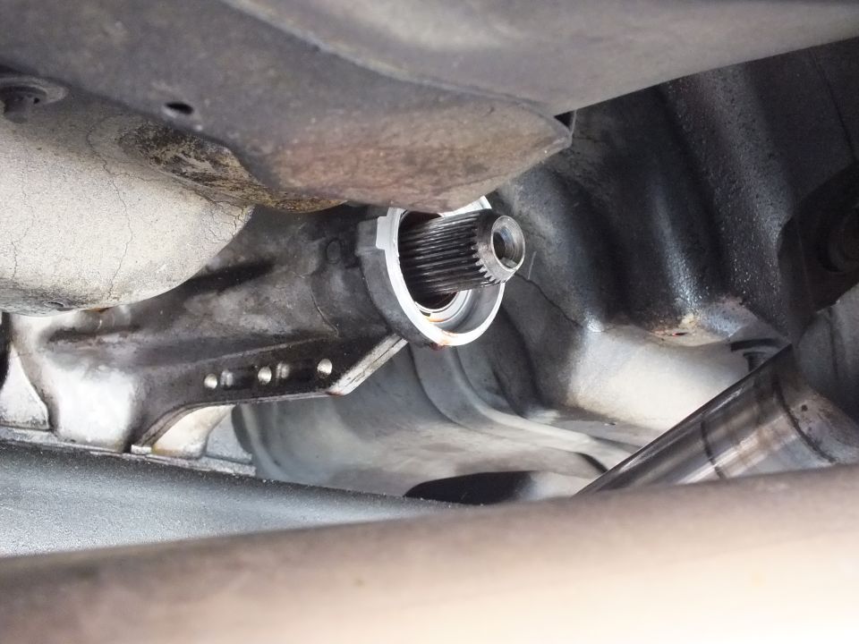 Close-up of splined output shaft end protruding from transmission housing under vehicle