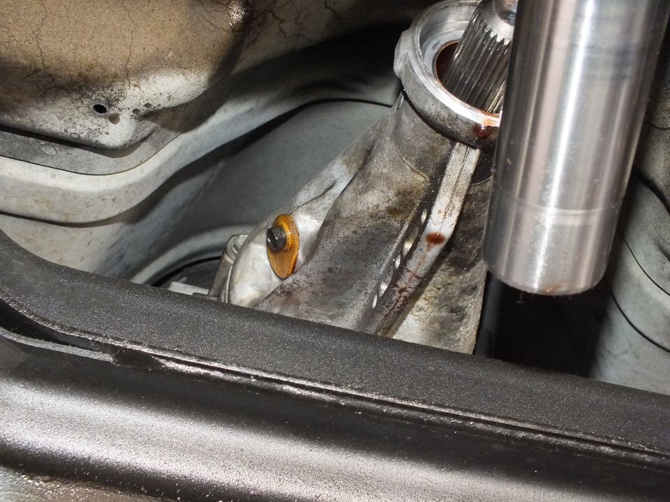 Polished driveshaft tube and splined yoke positioned over transmission housing under lifted vehicle