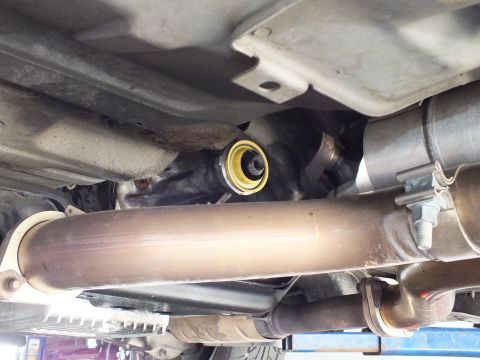2003 Ford Crown Victoria - yellow-collared seal surrounds the splined output shaft beside a driveshaft tube in this underbody close-up.