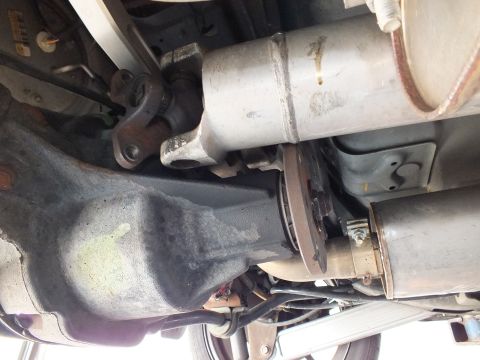 2003 Ford Crown Victoria - Rear differential, driveshaft flange and a metal catalytic converter shield appear beneath a raised vehicle.