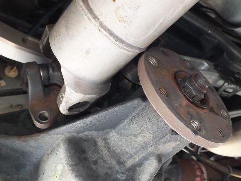2003 Ford Crown Victoria - driveshaft flange and differential pinion flange meet beneath the car, with a catalytic converter alongside.