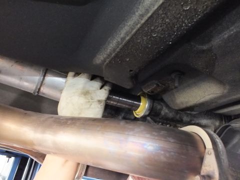 2003 Ford Crown Victoria - Driveshaft center support bearing seated above the exhaust crossover, shot from below on a shop lift.