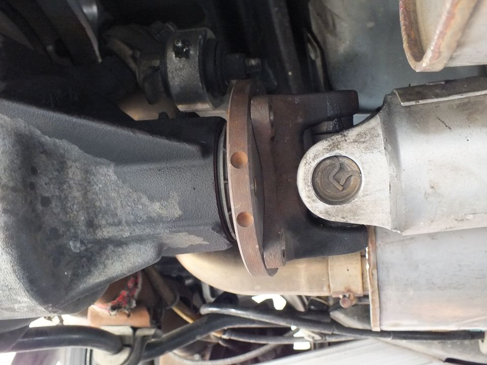 Rear differential pinion flange bolted to driveshaft U-joint yoke under a vehicle