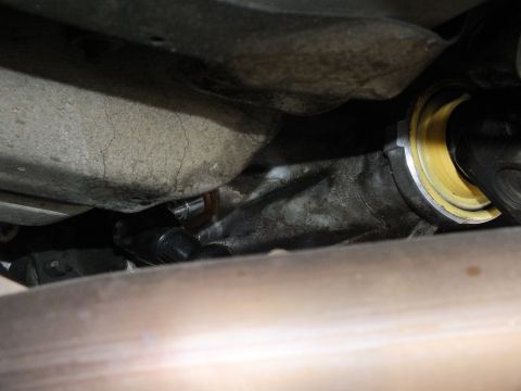 2003 Ford Crown Victoria - Slip yoke entering the transmission tailshaft seal, framed by exhaust piping below.