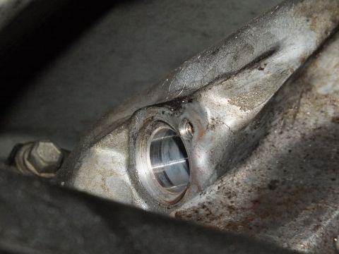 2003 Ford Crown Victoria - Close view of a machined bushing bore in a cast aluminum bracket with bolt at left.