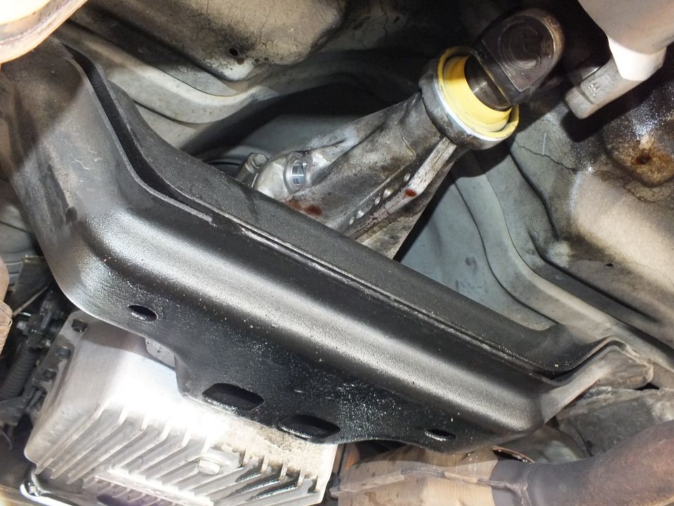 Black crossmember and driveshaft slip yoke above a finned aluminum transmission pan underbody