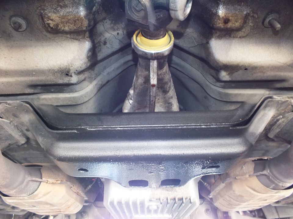 Driveshaft with yellow carrier bearing above black crossmember and finned transmission pan