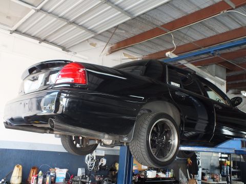 2003 Ford Crown Victoria - Lifted black Crown Victoria rear three-quarter with dual tips and Ford center cap wheel.