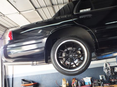 2003 Ford Crown Victoria - Front fender and black multi-spoke wheel of the lifted sedan with Supermotors decal.