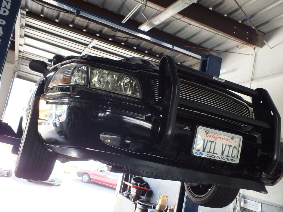 Front of black Ford Crown Victoria on a lift with brush guard and California VIL VIC plate
