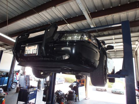 2003 Ford Crown Victoria - Front three-quarter underbody of the raised black Crown Victoria with the EVIL VIC plate.