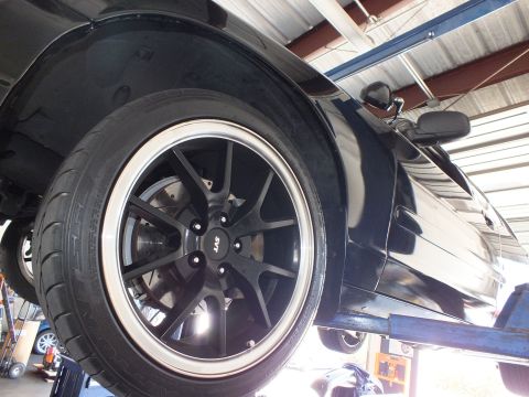 2003 Ford Crown Victoria - Black SVT-style wheel and performance tire on the lifted sedan, mirror above.