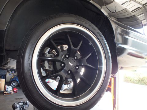2003 Ford Crown Victoria - Black multi-spoke wheel wrapped in a Nitto tire over a disc brake on the lifted car.