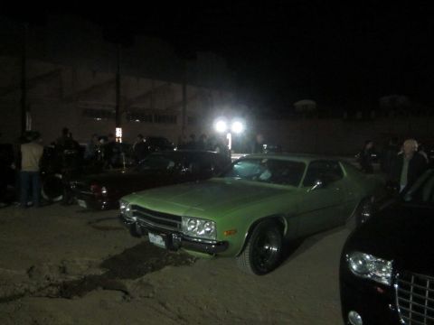 1991 Ford LTD Crown Victoria - A green muscle car is parked at a nighttime car meet with other vehicles and people in the background.
