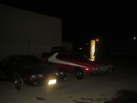 1991 Ford LTD Crown Victoria - Two vintage cars and a pickup truck are parked outside at night near a building.