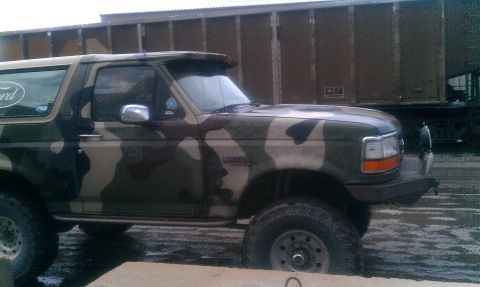 1995 Ford Bronco - This Ford Bronco has a camouflage paint job and is parked in a muddy area.