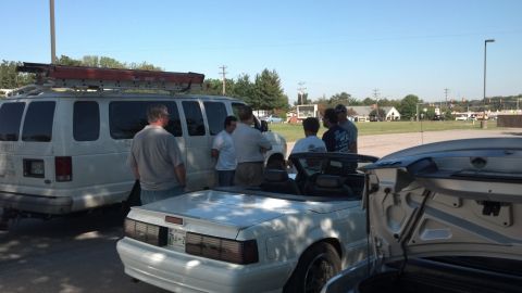 2007 Ford Mustang - A white convertible Mustang with its top down is parked next to a van and another vehicle.