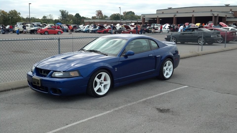 Blue 2007 Ford Mustang coupe with white rims parked at a car show