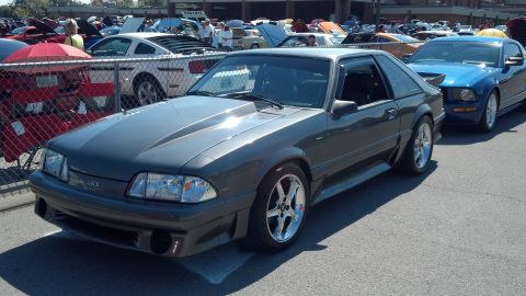 2007 Ford Mustang - A dark gray Ford Mustang is parked at a car show, with a blue Mustang behind it.