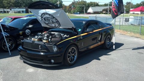 2007 Ford Mustang - A black 2007 Ford Mustang is displayed with its hood open, revealing the engine and a Team Shelby flag.