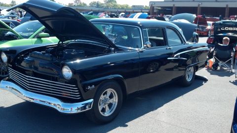 2007 Ford Mustang - A black 1955 Ford Fairlane sedan is displayed with its hood open at a car show event.