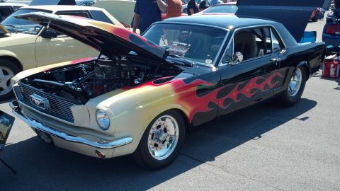 2007 Ford Mustang - Customized 1965 Ford Mustang with flame graphics and a prominent engine display at a car show.