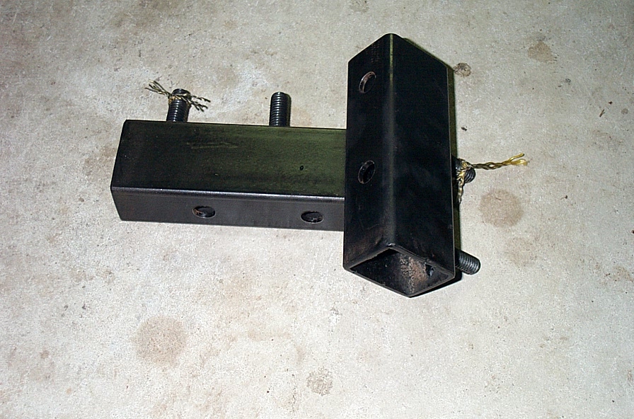 Welded square-tube hitch receiver drop bracket with U-bolts lying on a concrete floor