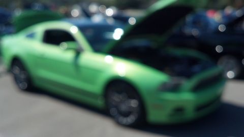 2007 Ford Mustang - A green 2007 Ford Mustang coupe is parked with its hood open at an outdoor car show.