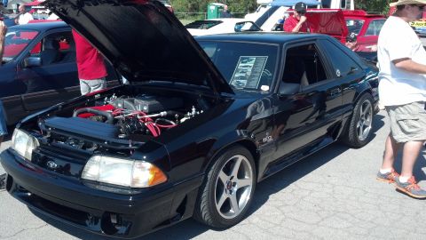 2007 Ford Mustang - Black 1987 Ford Mustang hatchback with hood open at a car show, other vehicles visible.