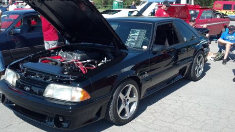 2007 Ford Mustang - A black Ford Mustang from the Fox body era is displayed with its hood open, revealing the engine bay.
