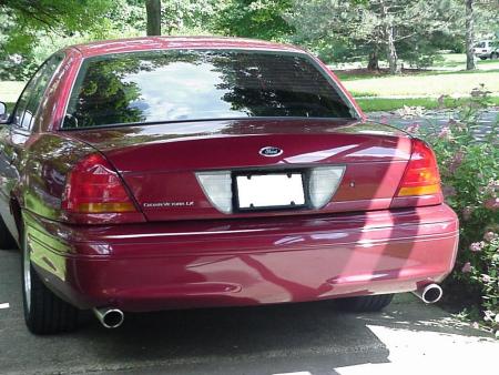 2002 Ford Crown Victoria - Rear view of a red 2002 Ford Crown Victoria LX, showing its taillights and dual exhaust pipes.
