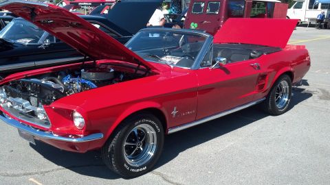 2007 Ford Mustang - A classic red Ford Mustang convertible is displayed with its hoods open at an outdoor car show.
